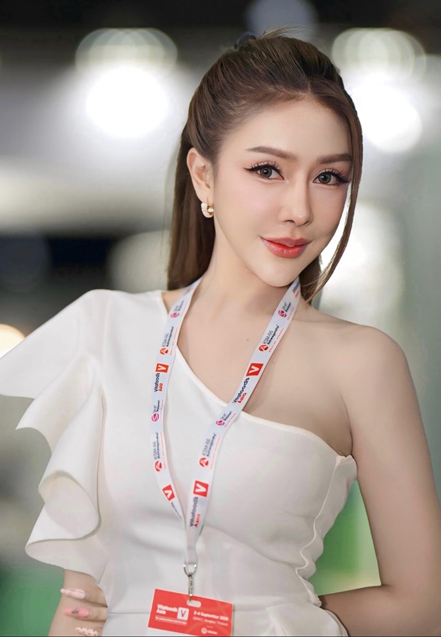 ลภัสท์วลัญ อายลิน ในชุดขาวไหล่เดียวพร้อมบัตรงานอีเวนต์