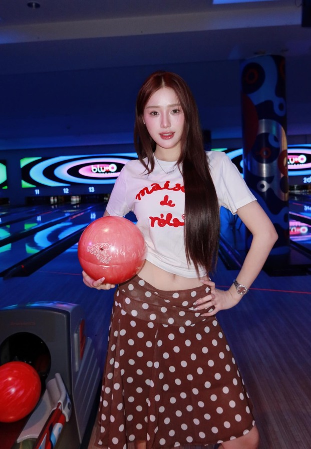 ขนม ถือลูกโบว์ลิ่งในเสื้อยืดขาวคู่กระโปรงลายจุด