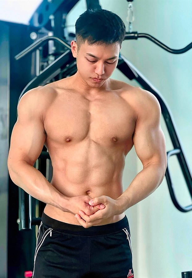 Jiraphong โพสท่าข้างเครื่องเล่นในห้องฟิตเนส