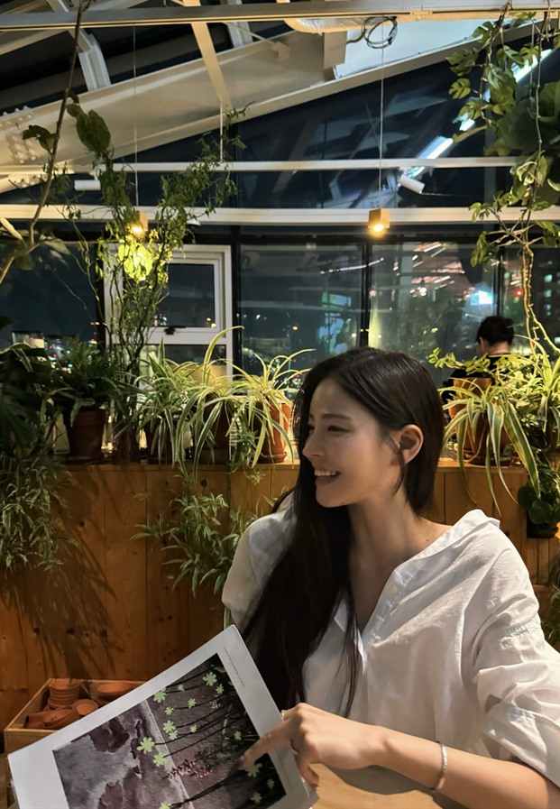 สาวเกาหลีในเสื้อปาดไหล่สีขาวมองกล้องท่ามกลางแสงไฟสลัวยามค่ำในร้านอาหาร