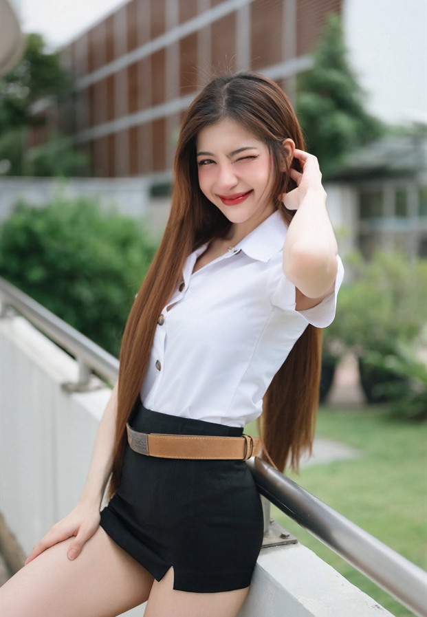 Natcha Chaiprapa ในชุดนักศึกษาเสื้อเชิ้ตขาวกระโปรงสั้นสีดำคาดเข็มขัดน้ำตาล